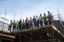 Twelve roofers lined up on the scaffolding that's been erected surrounding the building.