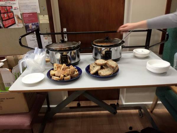A table with two slow cookers bubbling away and a selection of breads to go with the meal.