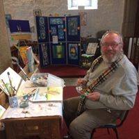 Bruce sitting in front of a table laden with painting gear.