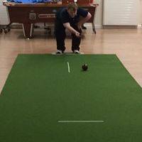 Kieran crouched down, having just released a black ball down a strip of green felt.